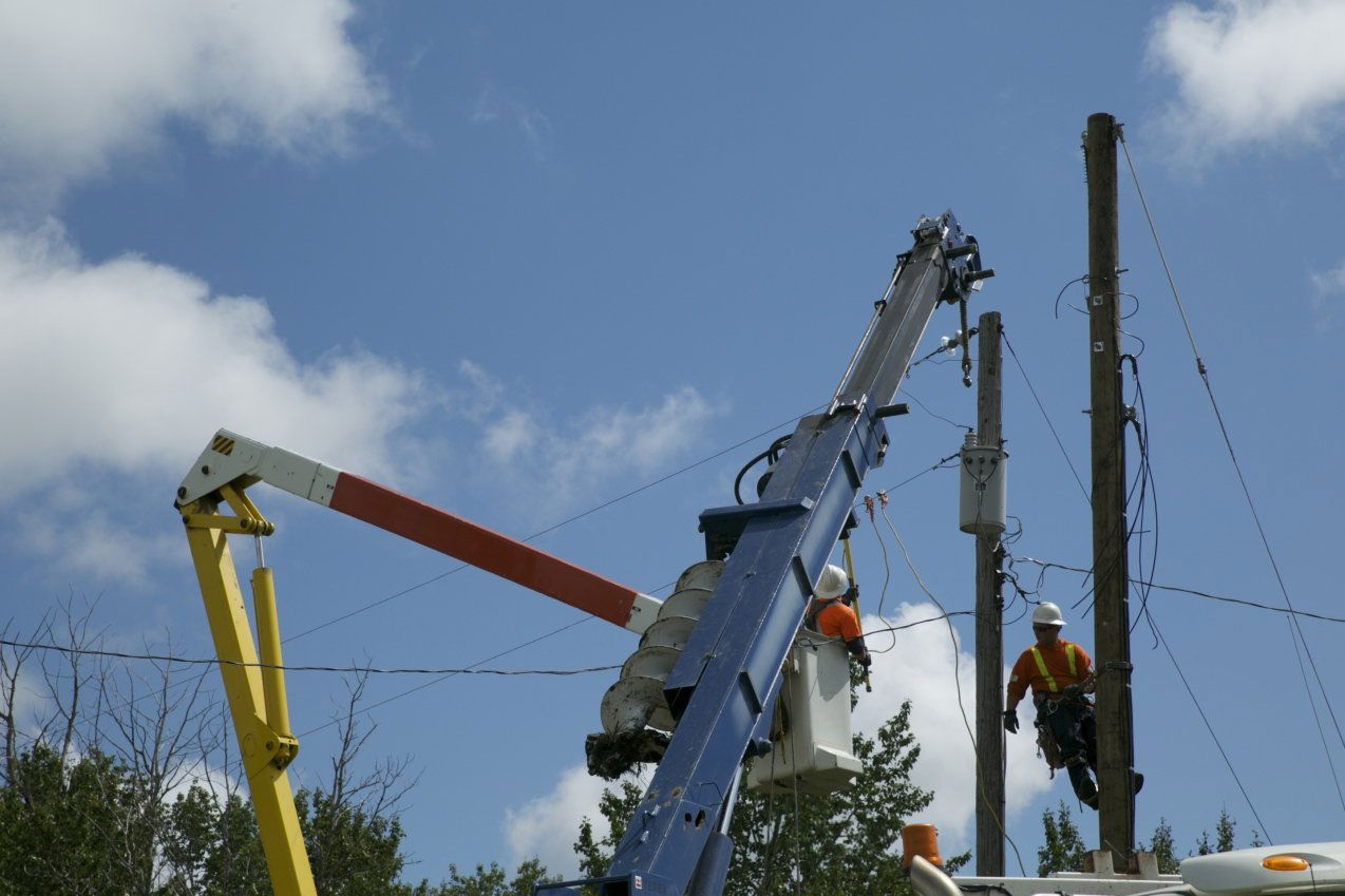 Two men on lift replace power pole